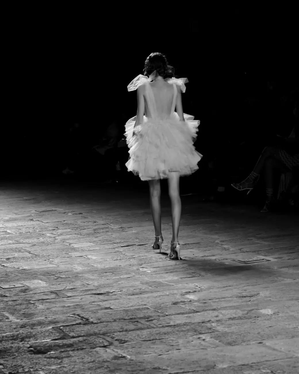 A model walks away down a dark runway